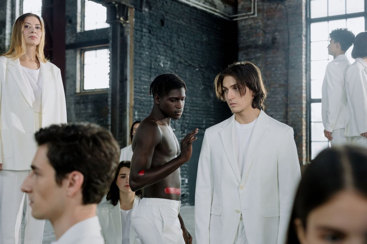 Models in a fashion shoot wearing white outfits in an industrial space.