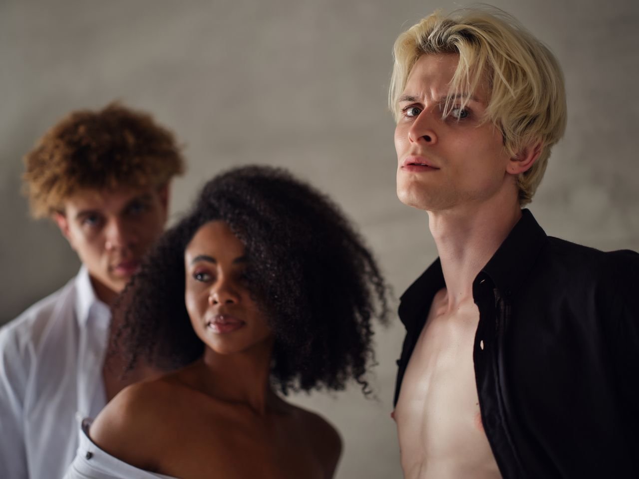 Stylish portrait of diverse young adults in fashionable attire with a dramatic look.