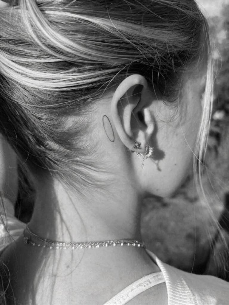 minimalist halo tattoo behind a woman's ear