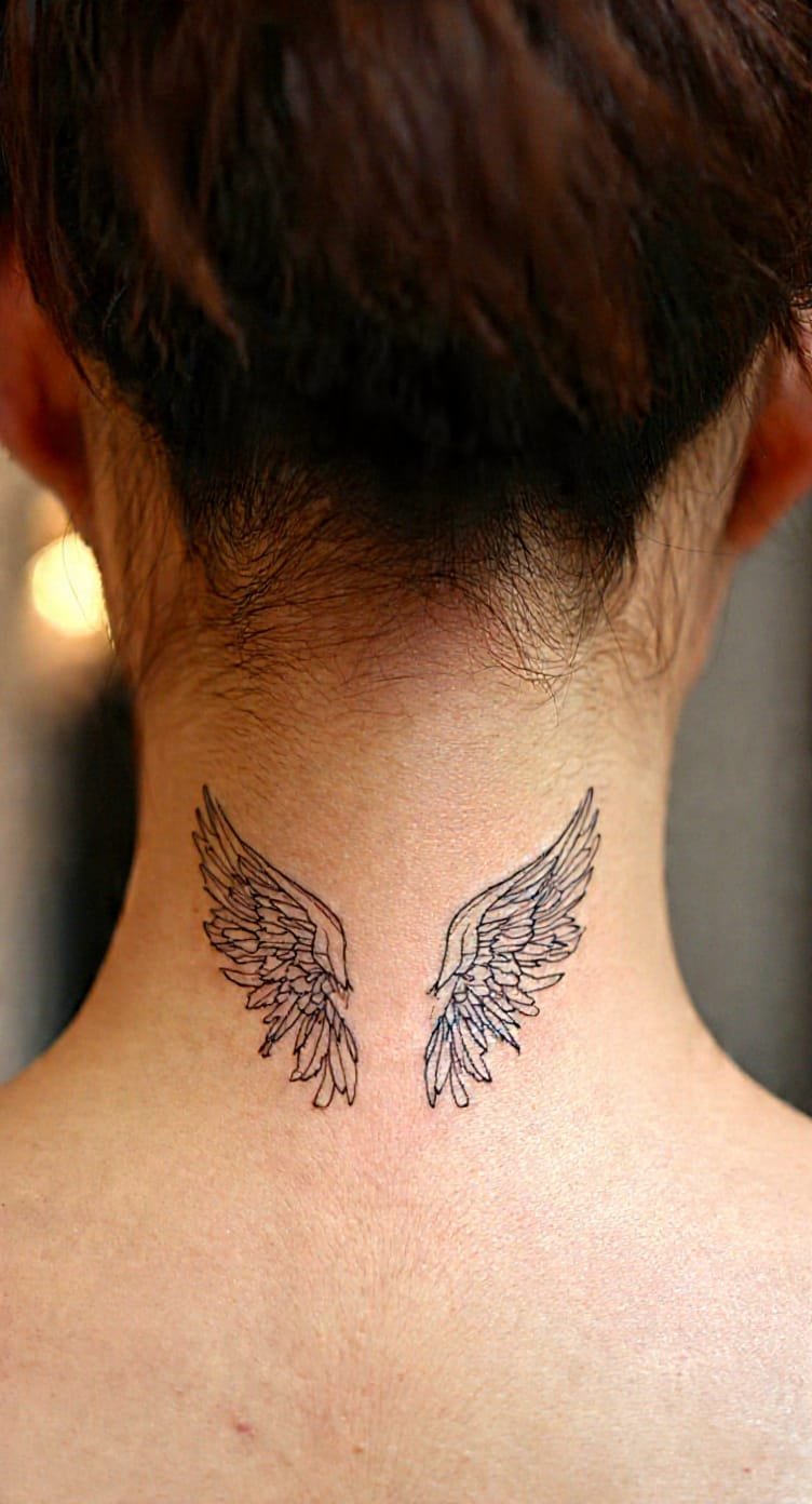Small minimalist line-work wings tattoo on the nape of the neck